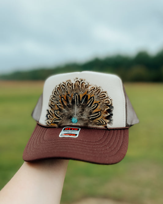 tan/brown feather trucker hat with turquoise